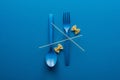 Top view of spaghetti on blue plastic spoon upside down and fork near farfalle pasta on blue background. Royalty Free Stock Photo