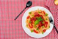 Top view of spaghetti pasta with a delicious homemade tomato sauce with homemade basil leaves served on a white plate on a red Royalty Free Stock Photo