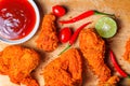 Top view of spicy fried chicken with tomatoes, chili, lime and ketchup on wooden tray