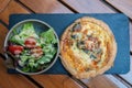 Top view of a spinach and salmon quiche and salad on the side on a board