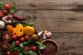 Top view of spinach and sliced tomatoes on plate near garlic, chilli pepper and bowl with pepper on wooden table. Royalty Free Stock Photo