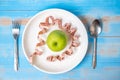 Top view spoon and fork, green apple in white dish with pink Measuring tape on blue wood table background. dieting , weight loss