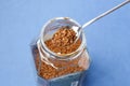 Top view of spoon in glass jar with instant coffee on blue table. Spoon with a granular coffee jar over Royalty Free Stock Photo