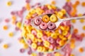 Top view of a spoon with multicolored fruity cereals and milk on a blurred background