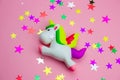 squishy toy unicorn and glitters in the shape of stars on pastel pink background