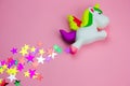 squishy toy unicorn and glitters in the shape of stars on pastel pink background