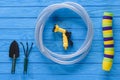 top view of stack of colorful flowers pots, gardening tools and hose on blue