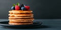 Top view of a stack of fluffy pancakes on white plate, drizzled with maple syrup and topped with fresh berries Royalty Free Stock Photo