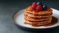 Top view of a stack of fluffy pancakes on white plate, drizzled with maple syrup and topped with fresh berries Royalty Free Stock Photo
