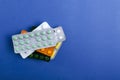 Top view of stack of various pills in the blister packs on the blue background.Empty space for text Royalty Free Stock Photo