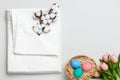 Top view of a stack of white bedsheets sets, cotton branch and a basket with Easter eggs. Copy space Royalty Free Stock Photo