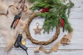 Top view of stages of making Christmas wreath with fir branches and decorative toys on wooden rustic tabletop