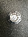 Top view of a stainless steel sink strainer on a gray background