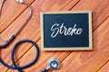 Top view of stethoscope and blackboard written with Stroke on wooden background. Health concept.