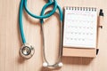 Top view of stethoscope on calendar for health checkup concept., Annual doctor appointment for physical check-up against wooden