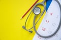 Top view of stethoscope and calendar on the yellow and blue background Royalty Free Stock Photo