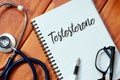 Top view of stethoscope,pen,eyeglasses and notebook written with Testosterone on wooden background. Royalty Free Stock Photo