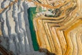 Top view on a stone quarry. Arial view on a mining of natural resources or ore. Green river separates white and yellow sand shores