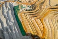 Top view on a stone quarry. Arial view on a mining of natural resources or ore. Green river separates white and yellow sand shores