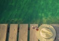 Top view of straw hat and sunglasses on wooden bridge over emerald green sea water. Summer vacation travel background. Summer vibe