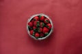 Top view of strawberries in bowl on red background bouquet of peonies Royalty Free Stock Photo