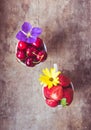 Top view of strawberries, cherries and yellow and purple flowers in bowls on wooden background Royalty Free Stock Photo