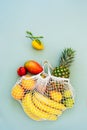 Top view string bag, mesh bag, grocery bag with organic fresh exotic fruits spilling from a reusable shopping bag on