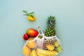 Top view string bag, mesh bag, grocery bag with organic fresh exotic fruits spilling from a reusable shopping bag on