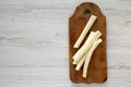 Top view, string cheese on rustic wooden board over white wooden background, top view. Healthy snack. Copy space