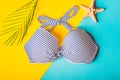 Top view of striped blue and white swimming bra and starfish on blue and yellow pastel background. Copy space. Concept