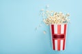 top view of striped carton bucket with popcorn on blue, cinema concept. Royalty Free Stock Photo