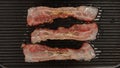 TOP VIEW: Strong fried a strips af bacon on a black pan