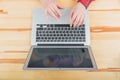 Top view of a stylish wooden office desk with a keyboard, a gray laptop and notebook and pen, working mans hands. Royalty Free Stock Photo