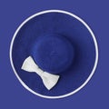 Top view summer beach round straw blue hat with white bow isolated in blue background