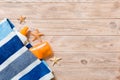 Top view of summer beach staff with copy space. Seashells or seastar, a bottle of suncream and blue towel on wooden background. Royalty Free Stock Photo