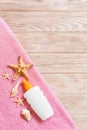 Top view of summer beach staff with copy space. Seashells or seastar, a bottle of suncream and pink towel on wooden background.