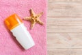 Top view of summer beach staff with copy space. Seashells or seastar, a bottle of suncream and pink towel on wooden background. Royalty Free Stock Photo