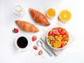 Top view summer breakfast with bowl of healthy fresh fruit salad, coffee and croissants. Flat lay on white background Royalty Free Stock Photo