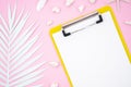 Top view summer clipboard mockup with a blank piece of paper and palm leaf on pink background. Flat lay with copy space Royalty Free Stock Photo