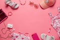 Top view with summer clothes. Children's clothes and accessories, phone, headphones, lipstick on pink background. Top