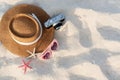Top view of summer holiday concept with straw hat, sunglasses, camera and coral in starfish shape on sand at the beach. Copy space Royalty Free Stock Photo