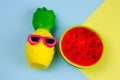 summer vibrant blue and yellow background with funny pineapple toy in sunglasses and squishy toy watermelon Royalty Free Stock Photo