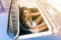 Top view from sunroof of a young beautiful woman sitting on car seat and drive carefuly.