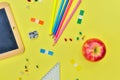 Suplies of school and red apple  on yellow background Royalty Free Stock Photo