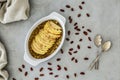 Top view of a sweet raw diet fruit dessert with slices of apple, dates scattered around and two teaspoons on a gray counter