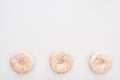 Top view of sweet whole doughnuts with sprinkles near bitten one on white background.