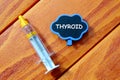 Top view of syringe and blackboard written with Thyroid on wooden background. Health concept.