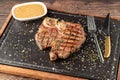 Top view of T-Bone Steak served on stone plate with sauce on the side Royalty Free Stock Photo