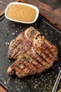 Top view of T-Bone Steak served on stone plate with sauce on the side Royalty Free Stock Photo