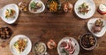 Top view of a table full of various meals for vegetarians and meat eaters served in a circle